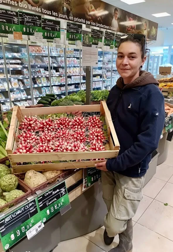 Dorine Poiraudeau avec une cagette de radis dans un magasin Colibri